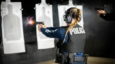 Female police office firing gun at range