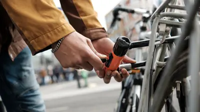 Cyclist Securing Bike With U Lock On City Street