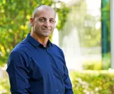 male in blue shirt in front of tree