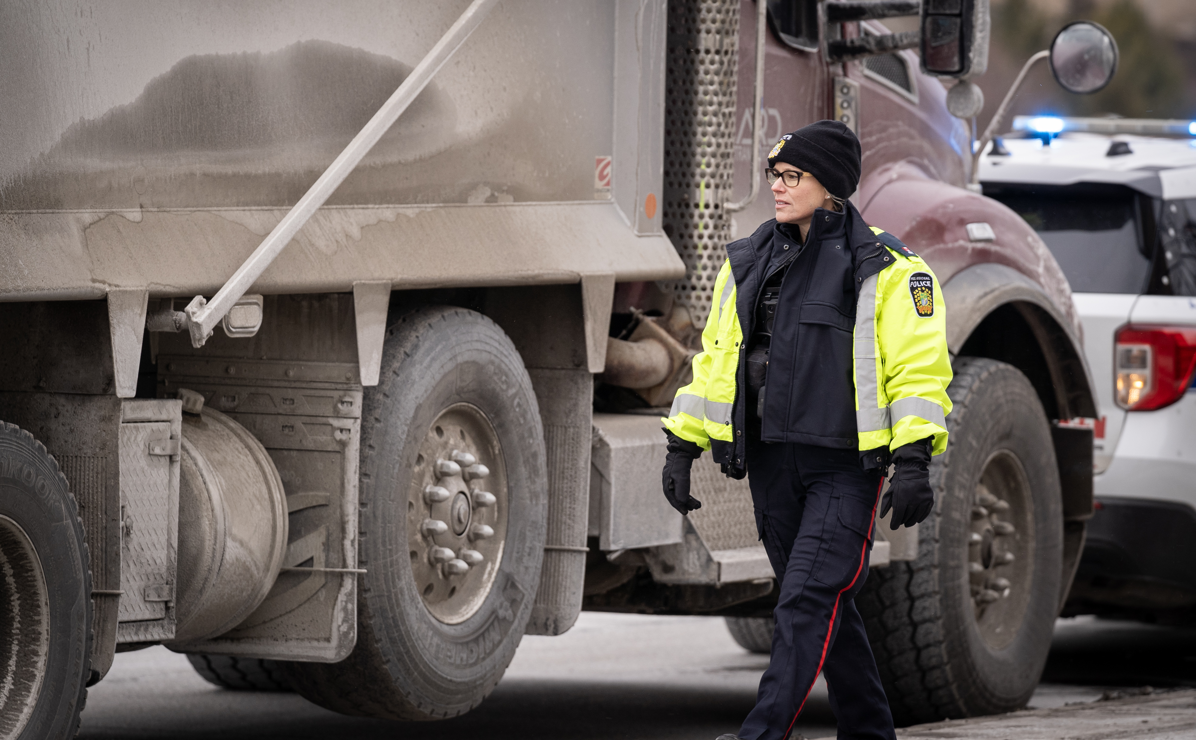 Female police officer inspecting truck during winter