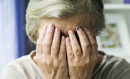 Elderly woman putting hands over face