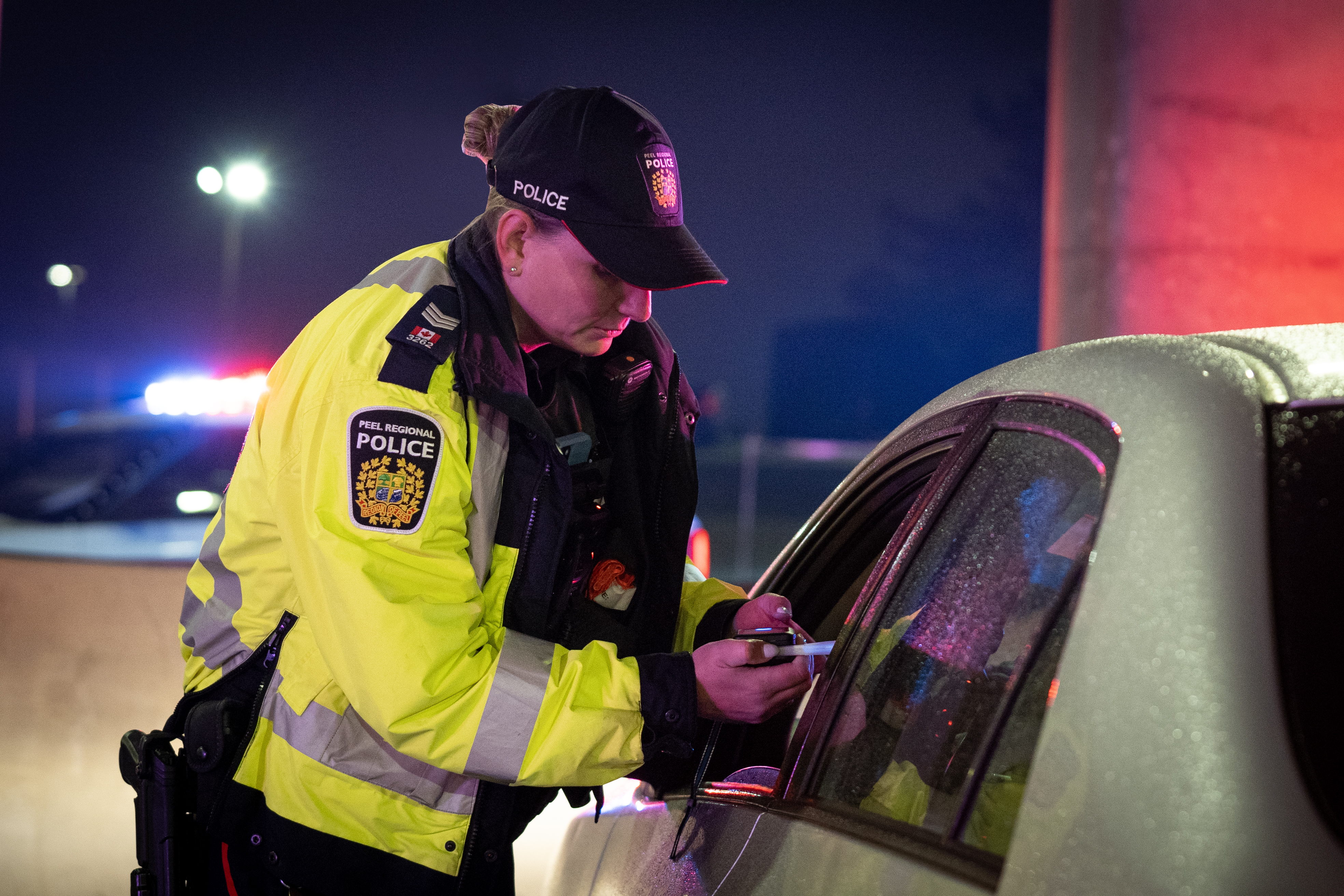 Female police officer administering breathalizer at night RIDE check