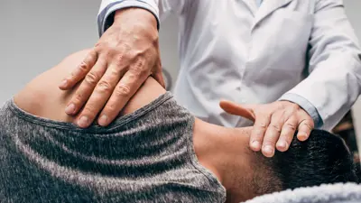 Chiropractor In White Coat Massaging Neck Of Man
